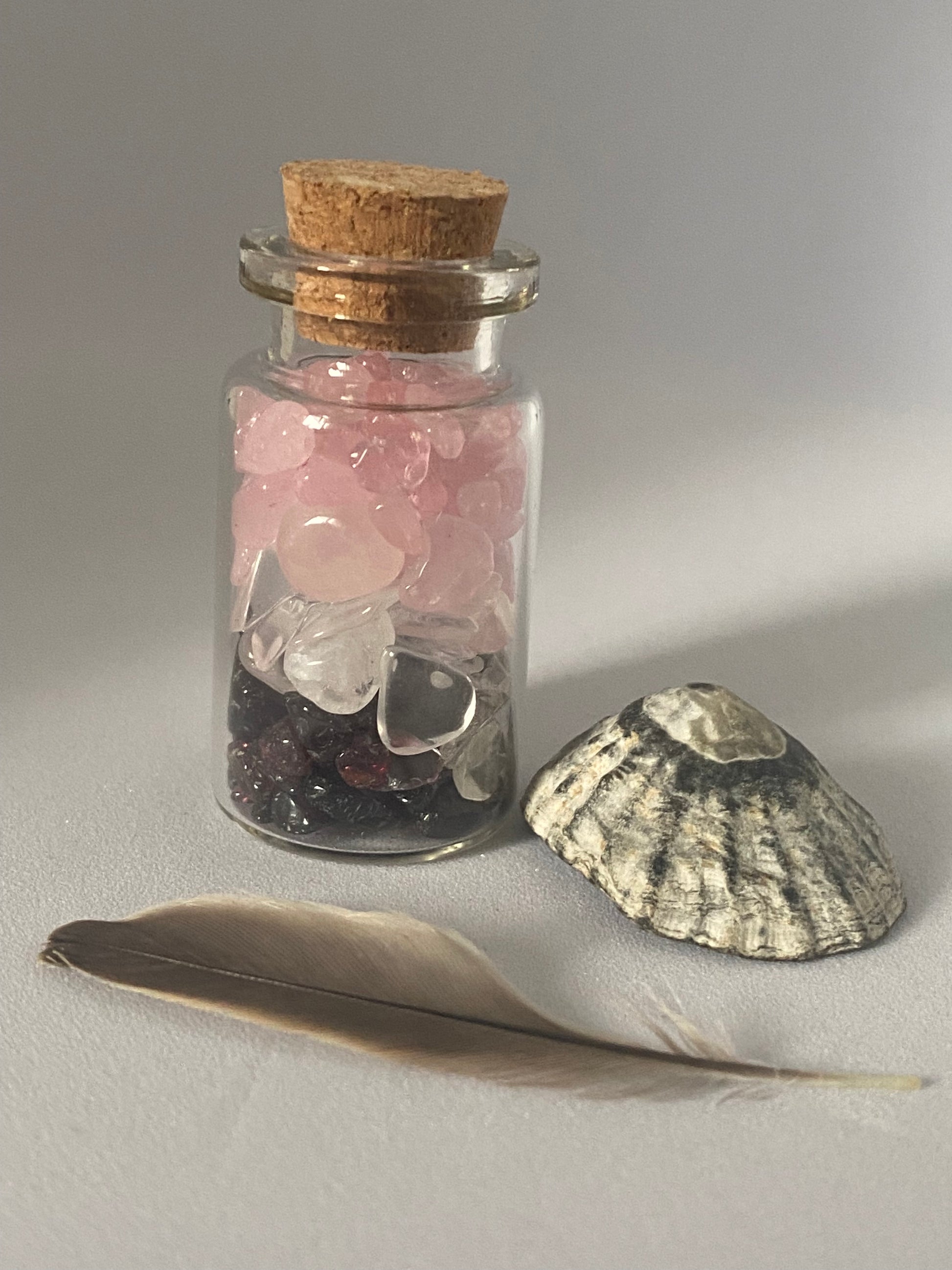 fiole d'intention ou spelljar, contenant des chips de pierre naturelle favorisant la guérison émotionnelle, grenat, quartz rose et cristal de roche